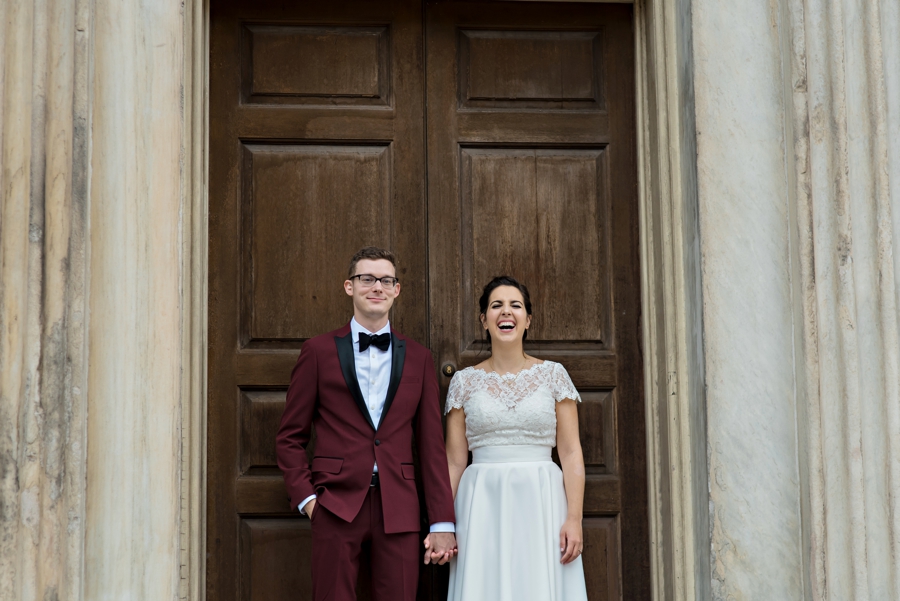 A bride and groom stand in front of a giant old door in old city Philadelphia.
